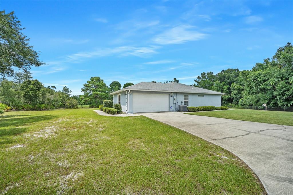 A single-story house with a white garage door and a concrete driveway sits on grass — 32543 PONDEROSA AVENUE, DELAND, FL