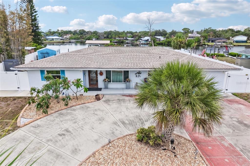 An exterior view of a single-story house with a concrete driveway and waterfront access — 806 BLUE HERON BOULEVARD, RUSKIN, FL