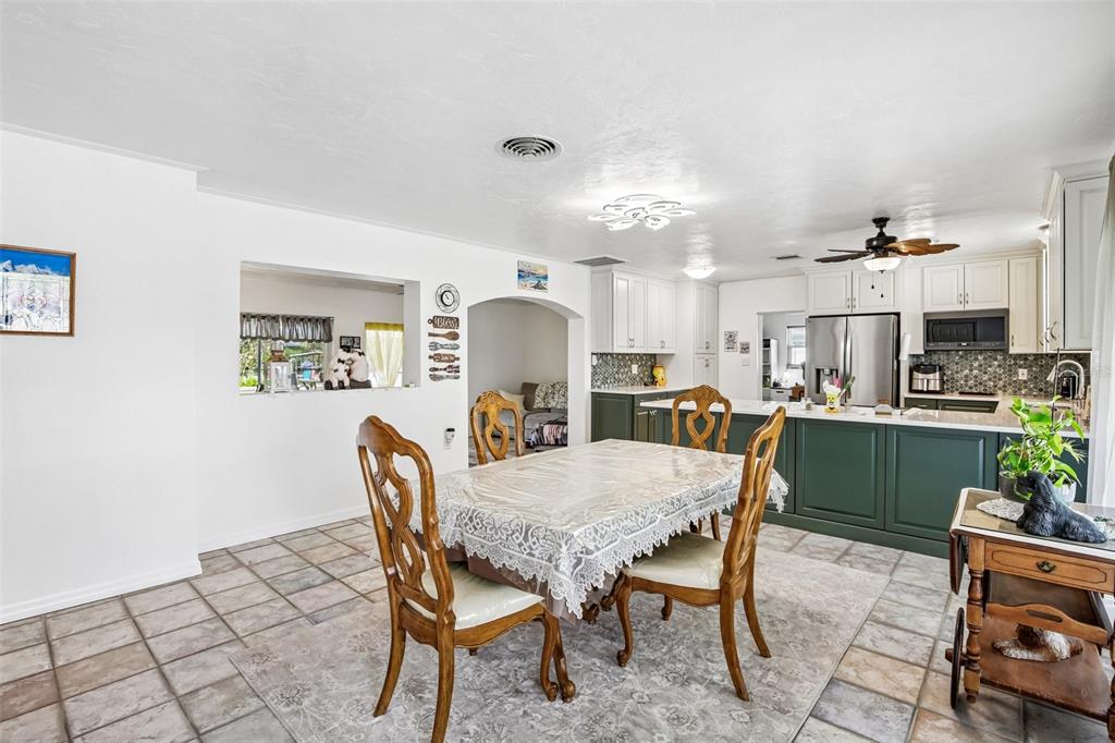 A dining area with a table and chairs sits adjacent to a kitchen with green cabinets — 806 BLUE HERON BOULEVARD, RUSKIN, FL