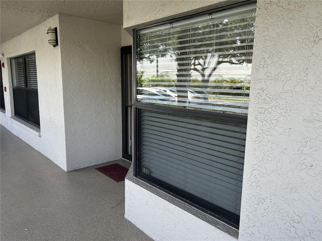 A view of a building exterior showing a walkway, a front door, and windows — 1316 PASADENA AVENUE S UNIT 102, SOUTH PASADENA, FL