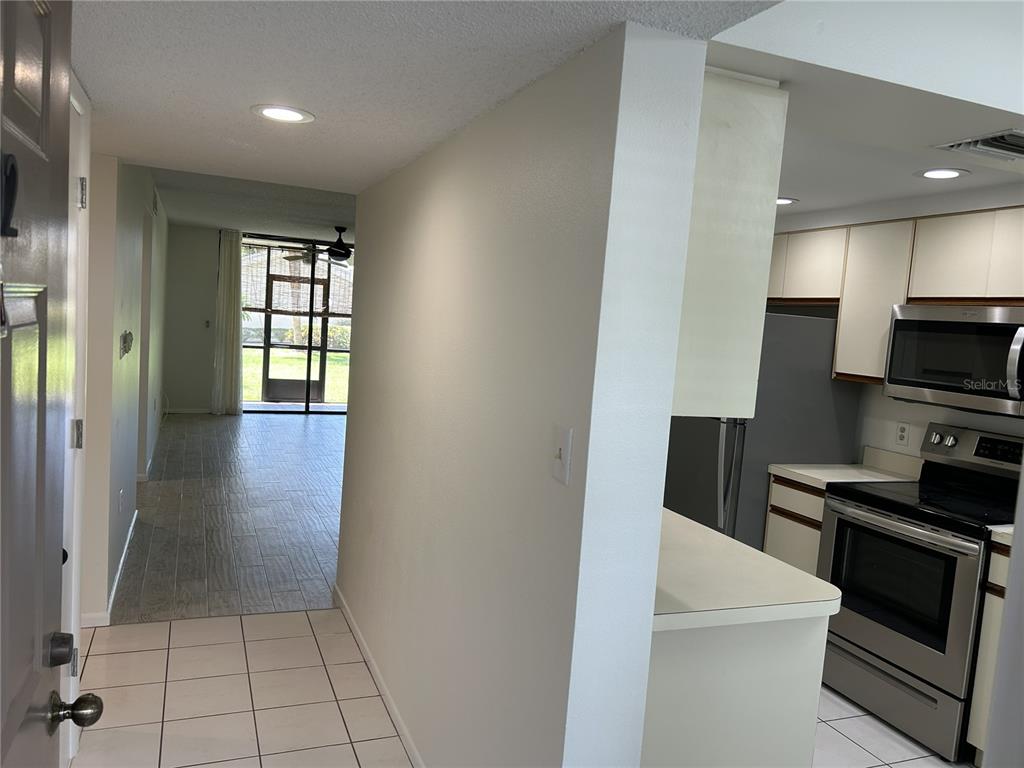 An entryway leads to a living area with tile floors and a view of a patio — 1316 PASADENA AVENUE S UNIT 102, SOUTH PASADENA, FL