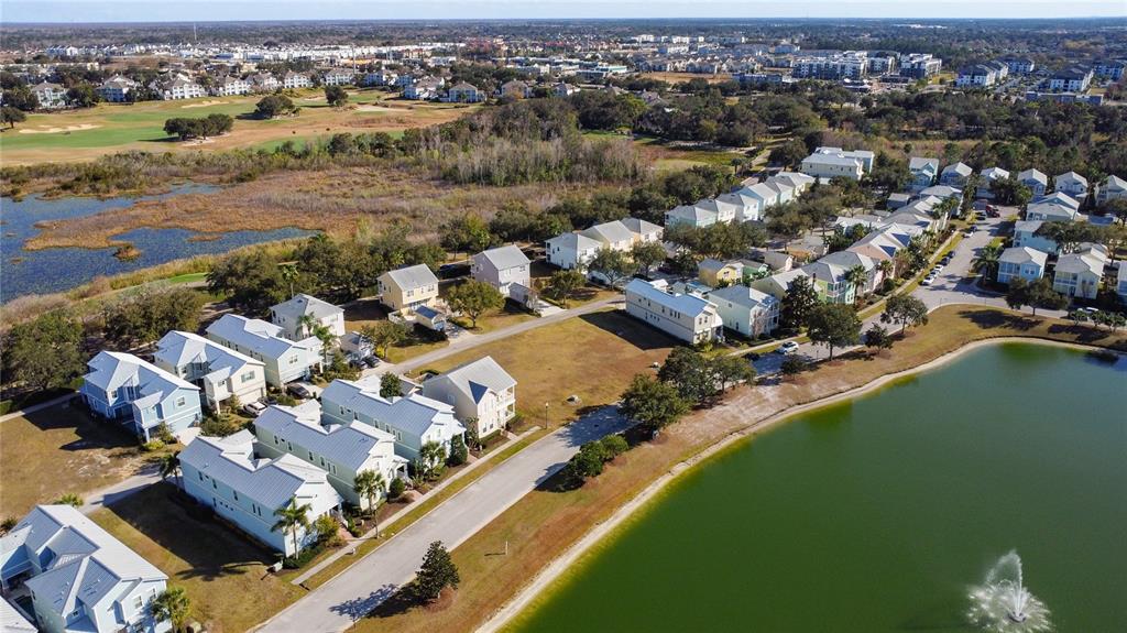 An aerial view shows a residential neighborhood with houses situated along a lake and wetlands — 1527 FAIRVIEW CIRCLE, REUNION, FL