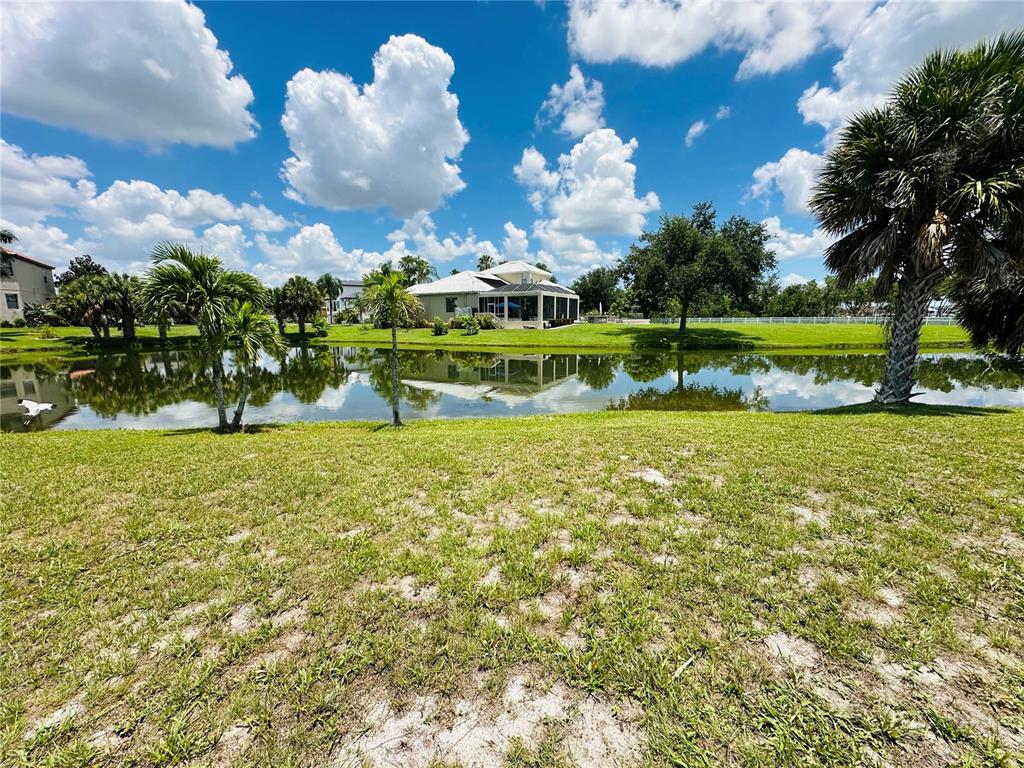 A view of a pond and lawn looking toward a house with a screened lanai — 1327 JUMANA LOOP, APOLLO BEACH, FL