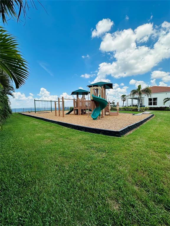 A playground with a slide and swing set sits on wood chips near a house — 1327 JUMANA LOOP, APOLLO BEACH, FL
