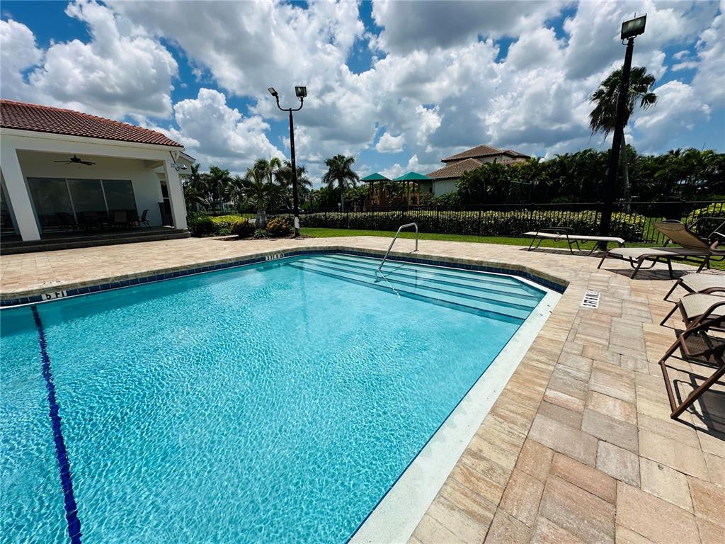 A swimming pool with steps and lounge chairs sits on a patio near a building — 1327 JUMANA LOOP, APOLLO BEACH, FL