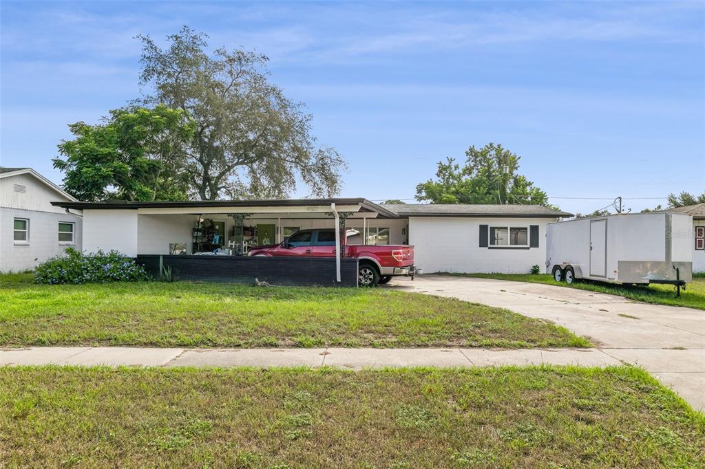 A white single-story house with a carport sits on a grassy lot with a tree — 4517 FETROW DRIVE, ORLANDO, FL