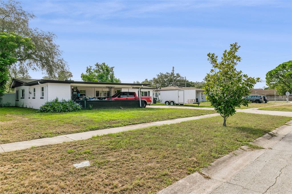 A white single-story house with a large carport, a red truck, and a utility trailer — 4517 FETROW DRIVE, ORLANDO, FL