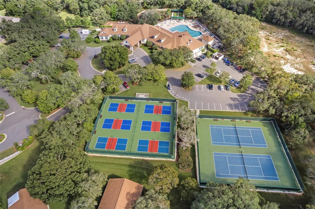 An aerial view shows a clubhouse with a pool, parking lot, and several tennis courts — 11578 NEW HAVEN DRIVE, SPRING HILL, FL