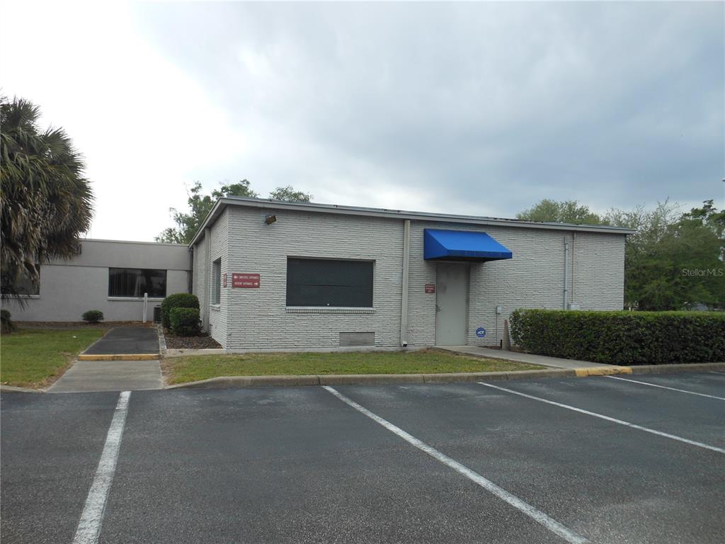 A single-story brick commercial building with a blue awning over the entrance and parking lot — 1109 SW 10TH STREET, OCALA, FL