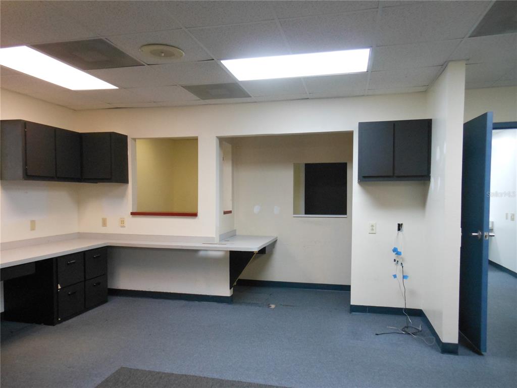 An office or commercial space with dark cabinets, a built-in desk, and blue carpeting — 1109 SW 10TH STREET, OCALA, FL