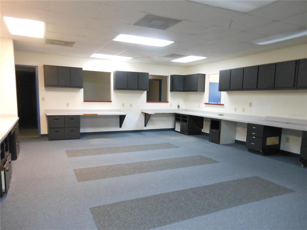 An office or workspace featuring gray cabinetry, light countertops, and blue carpeted flooring — 1109 SW 10TH STREET, OCALA, FL