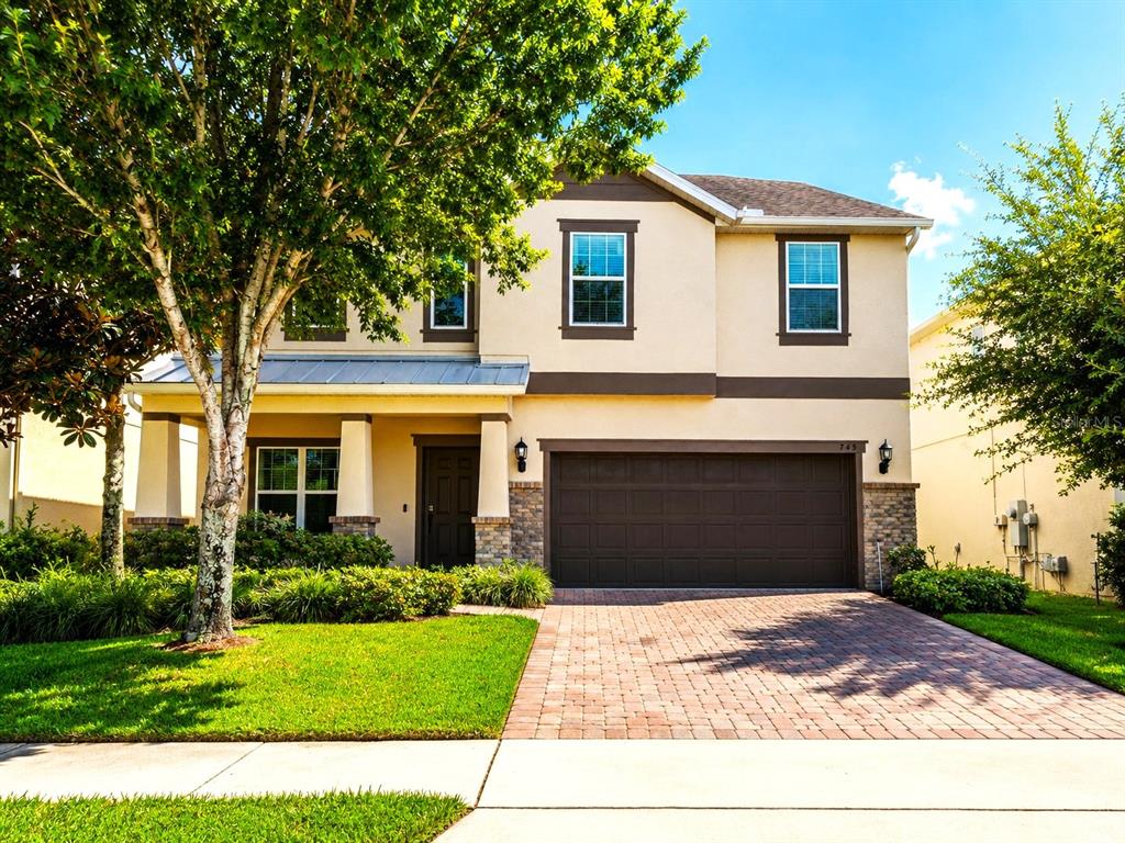 A two-story suburban house with a brick paver driveway, a garage, and a front porch — 745 MARSH REED DRIVE W, WINTER GARDEN, FL