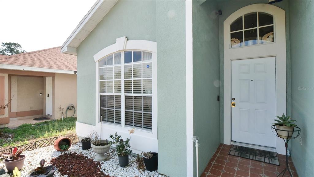 A light green house exterior features a white front door and a large arched window — 4381 CREEKSIDE BOULEVARD, KISSIMMEE, FL