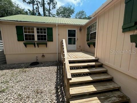 A wooden staircase leads to the front entrance of a light-colored house with green shutters — 526 KINGS CREEK CIRCLE, STEINHATCHEE, FL