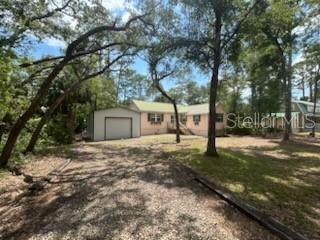 A single-story house with a detached garage sits on a wooded lot with a driveway — 526 KINGS CREEK CIRCLE, STEINHATCHEE, FL