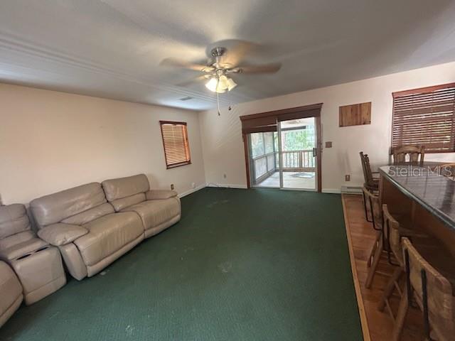 A living room with green carpet, a beige sectional sofa, and a sliding glass door — 526 KINGS CREEK CIRCLE, STEINHATCHEE, FL