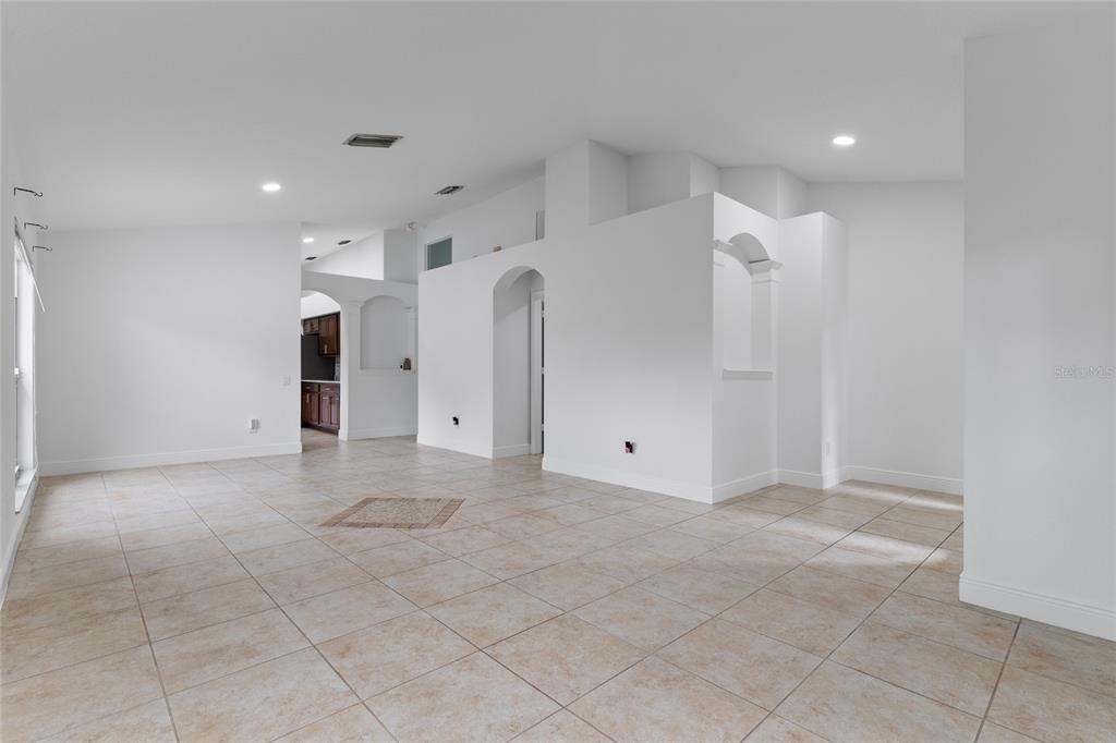 An open-concept living area features white walls, tile flooring, and arched architectural wall cutouts — 12315 TWINKLING STAR PLACE, RIVERVIEW, FL