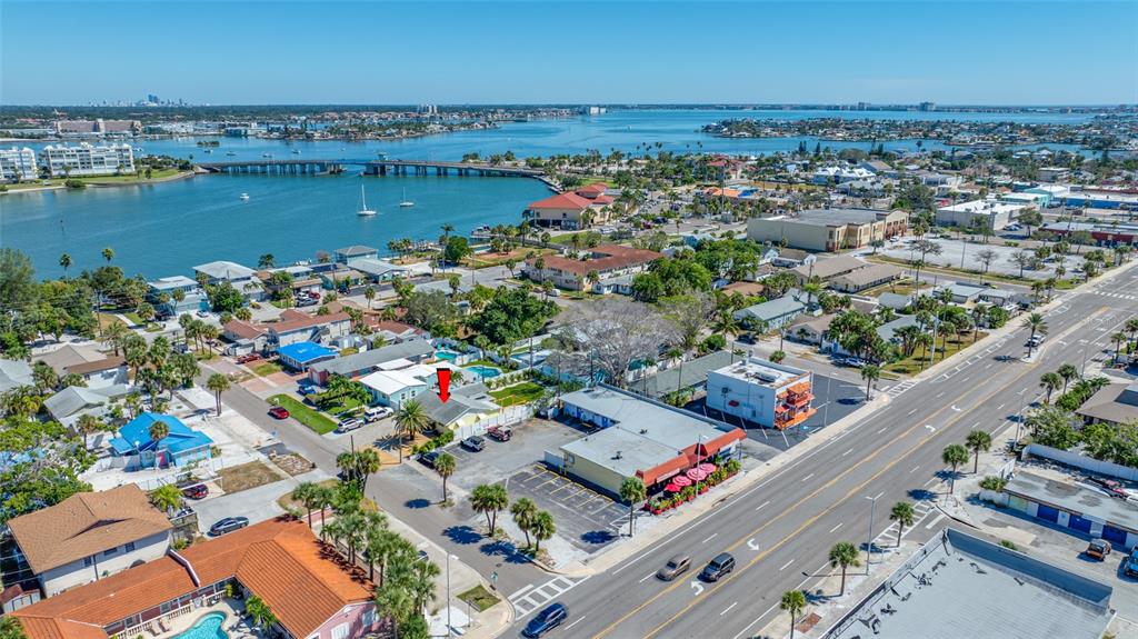 An aerial view shows a coastal neighborhood with a red arrow pointing to a house — 340 79TH AVENUE, ST PETE BEACH, FL