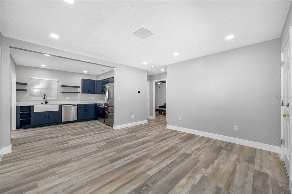 A kitchen with blue cabinets and stainless steel appliances opens into a gray living area — 340 79TH AVENUE, ST PETE BEACH, FL