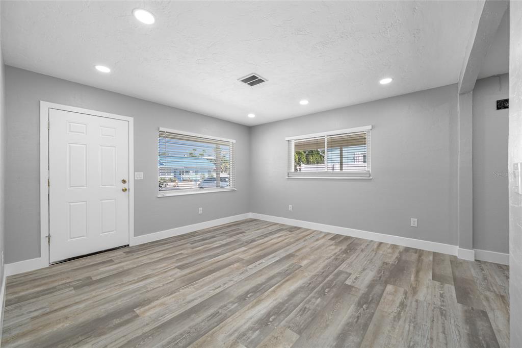 An empty room with gray walls, wood-look flooring, recessed lighting, and two windows — 340 79TH AVENUE, ST PETE BEACH, FL