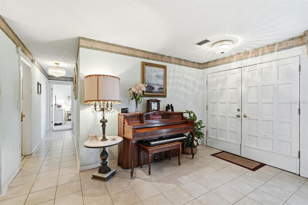 An entryway features tile flooring, a piano, a lamp, and double doors under a ceiling light — 2944 OCEAN SHORE BOULEVARD, ORMOND BEACH, FL