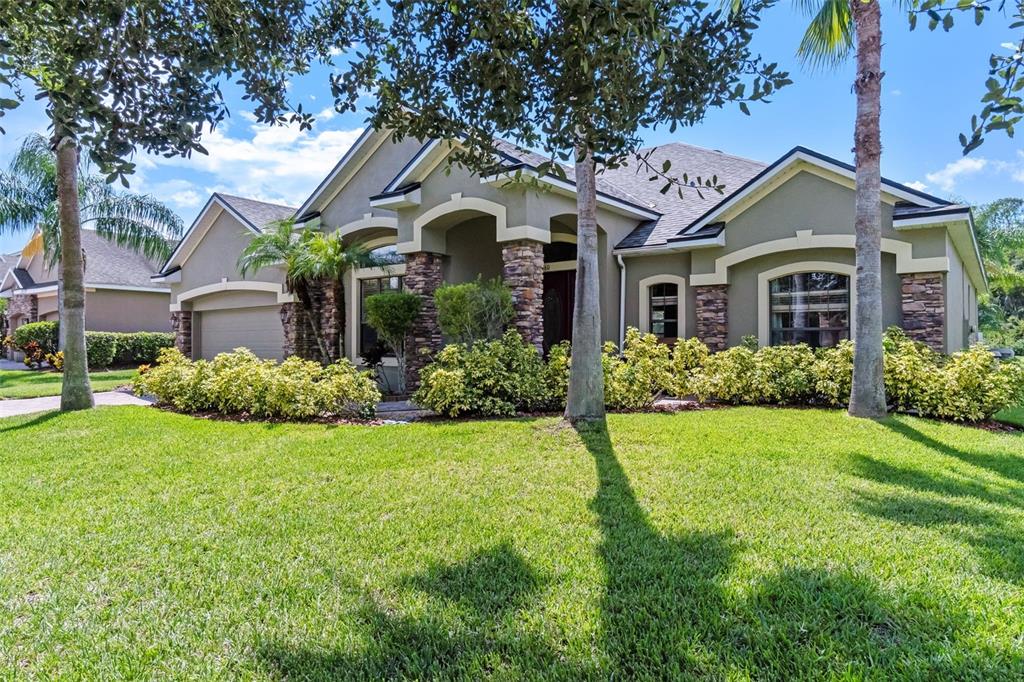 A single-story house with a stone-accented facade, arched entryway, and palm trees in the yard — 1460 PRAIRIE OAKS DRIVE, ST CLOUD, FL