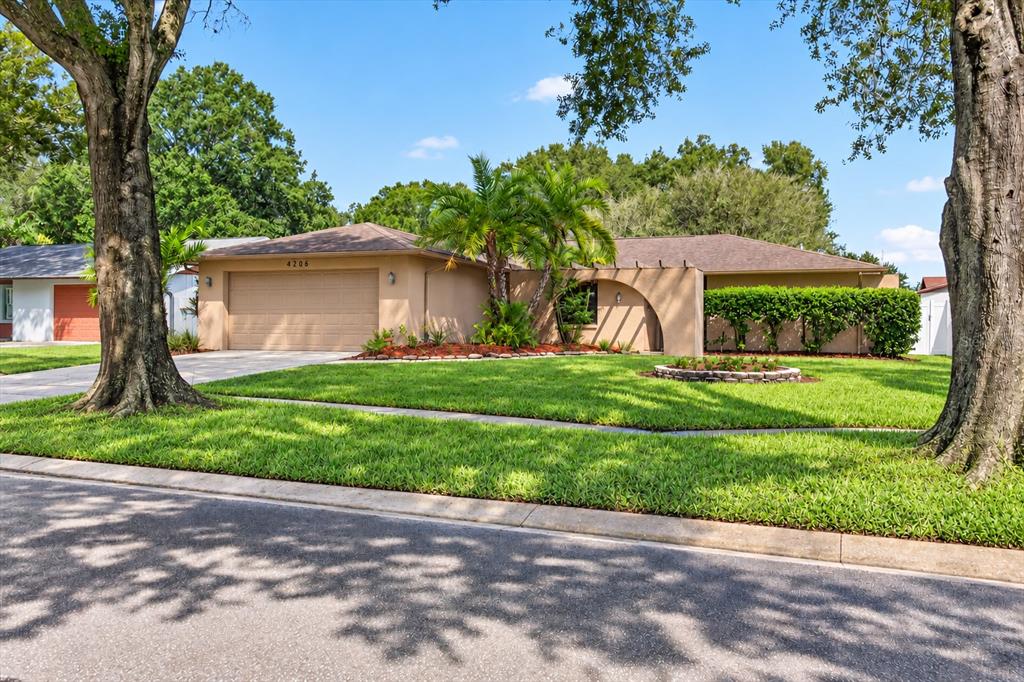 A single-story house with a tan exterior, a two-car garage, and a large front lawn — 4206 GRAINARY AVENUE, TAMPA, FL