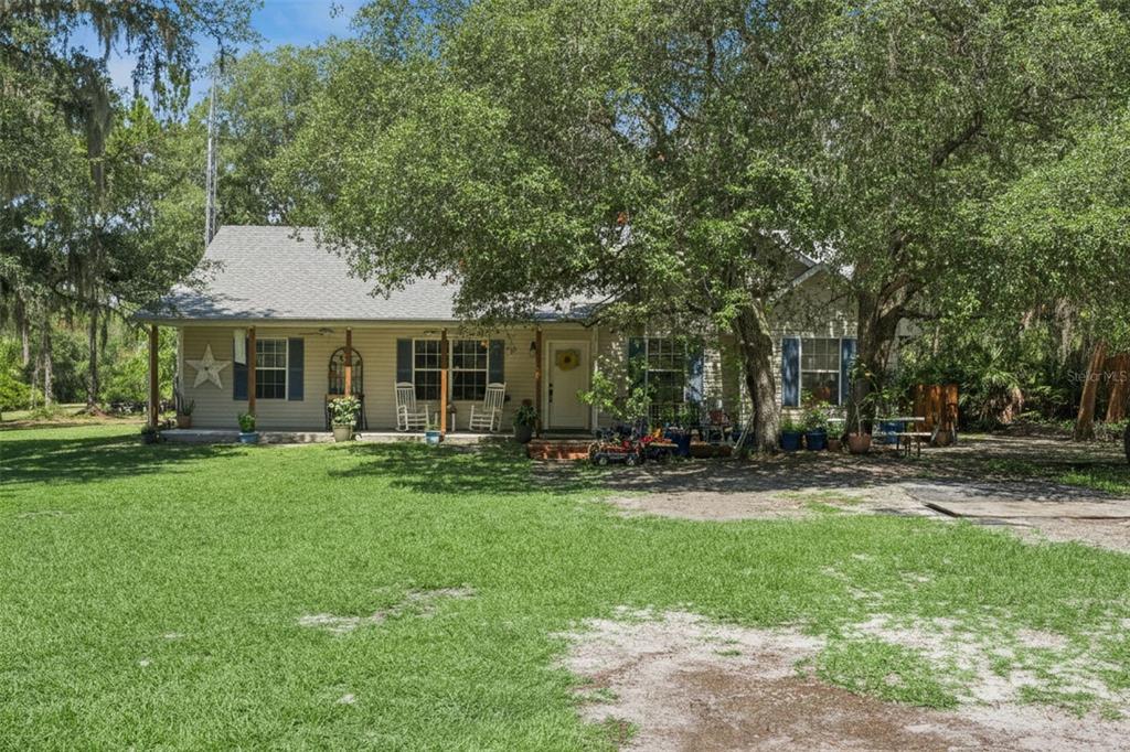 A single-story house with a covered porch sits on a large, tree-shaded grassy lot — 5500 VENTURA ACRES ROAD, GROVELAND, FL