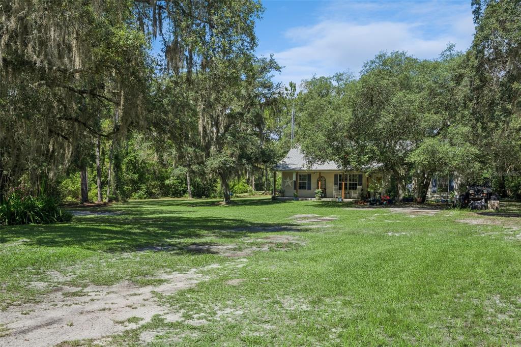 A living room features two brown leather sofas, a coffee table, and wood-look flooring — 5500 VENTURA ACRES ROAD, GROVELAND, FL