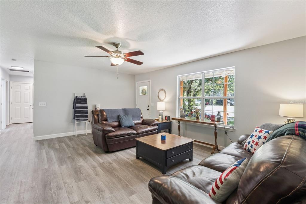 A living room features light-colored wood-look flooring, two brown leather sofas, and a ceiling fan — 5500 VENTURA ACRES ROAD, GROVELAND, FL