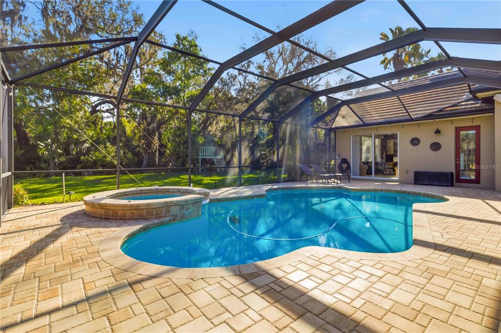 A screened-in patio features a swimming pool, a raised hot tub, and brick paver decking — 15108 KESTRELGLEN WAY, LITHIA, FL