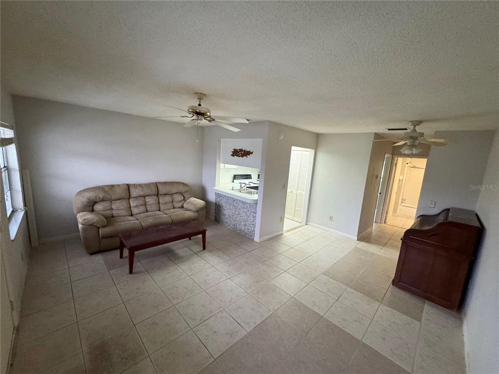 A living room with tile floors opens to a kitchen featuring a tiled breakfast bar — 1250 S PINELLAS AVENUE UNIT 511, TARPON SPRINGS, FL