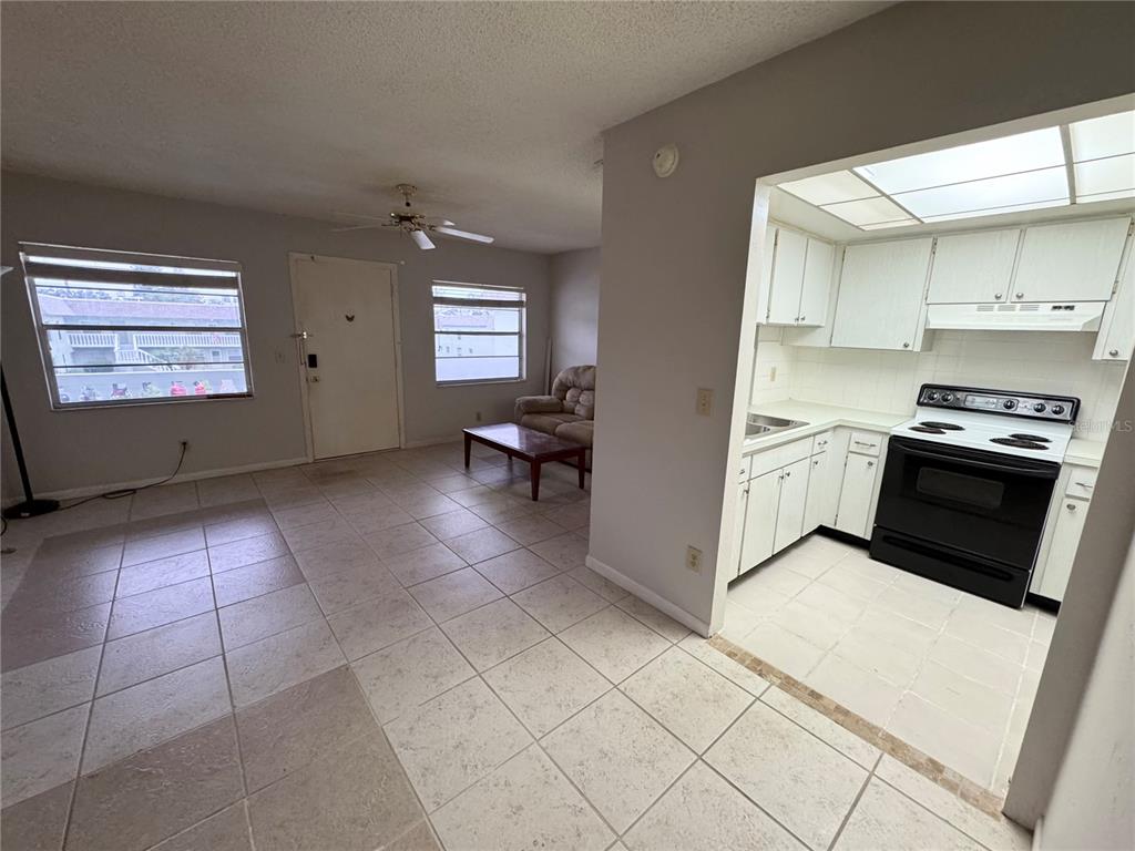A living room features tile flooring, a ceiling fan, a front door, and window curtains — 1250 S PINELLAS AVENUE UNIT 511, TARPON SPRINGS, FL