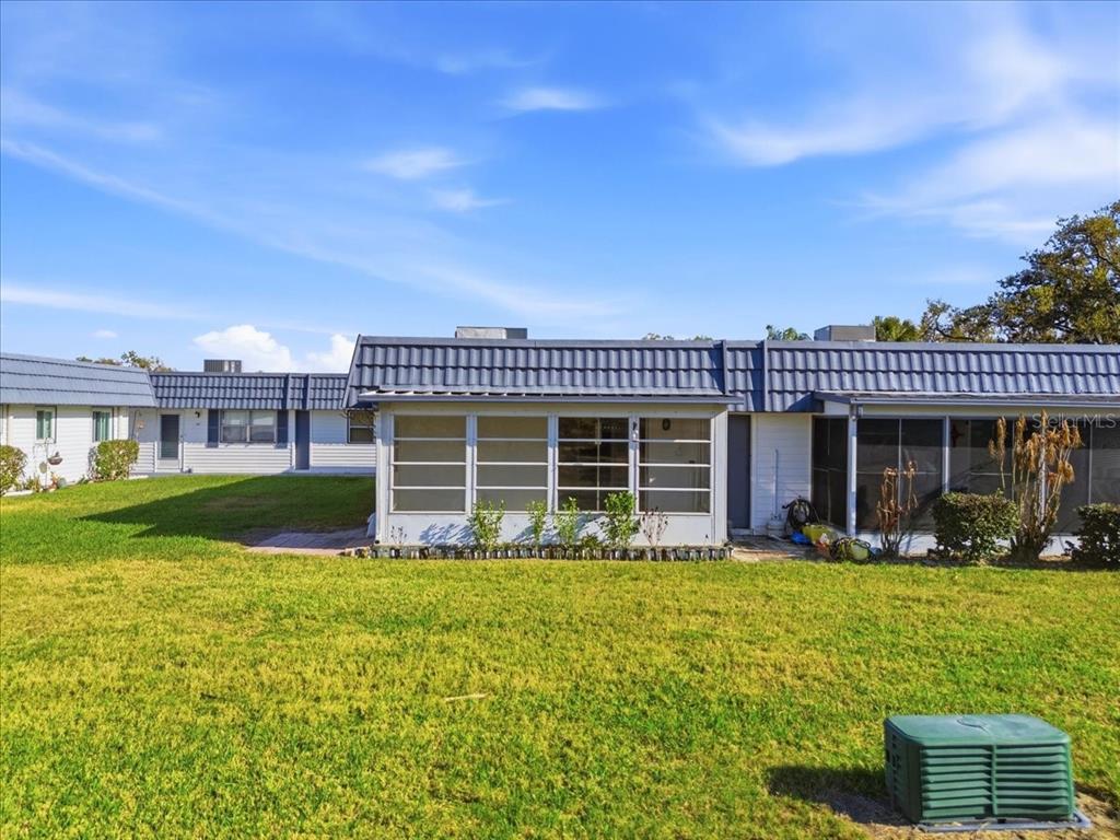 The exterior of a single-story residential building features a screened-in porch and a grassy lawn — 205 ANDOVER PLACE N UNIT 119, SUN CITY CENTER, FL