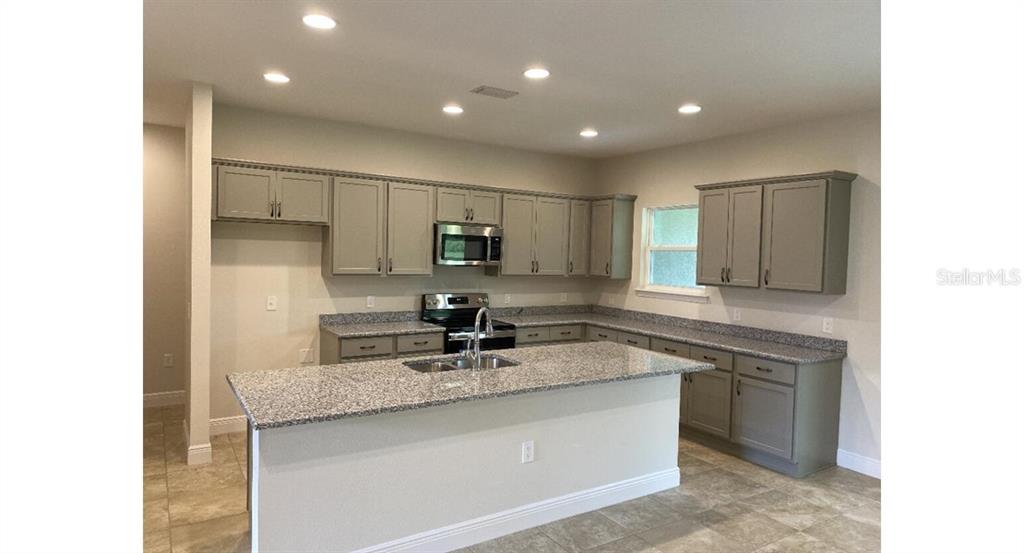 A kitchen features gray cabinets, granite countertops, a center island, and recessed lighting — 5519 BAKER ROAD, NORTH PORT, FL
