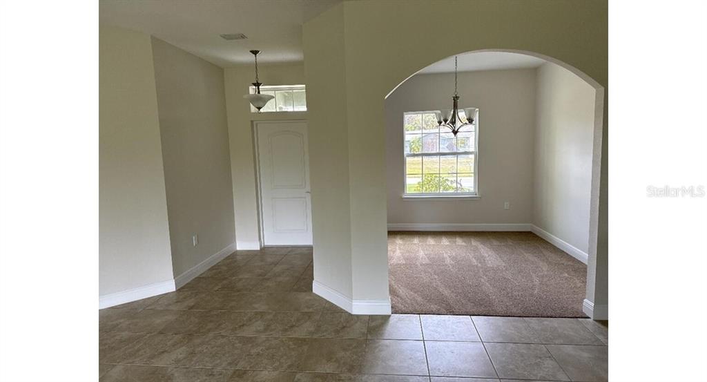 An entryway with tile flooring leads to a carpeted room through an arched opening — 5519 BAKER ROAD, NORTH PORT, FL