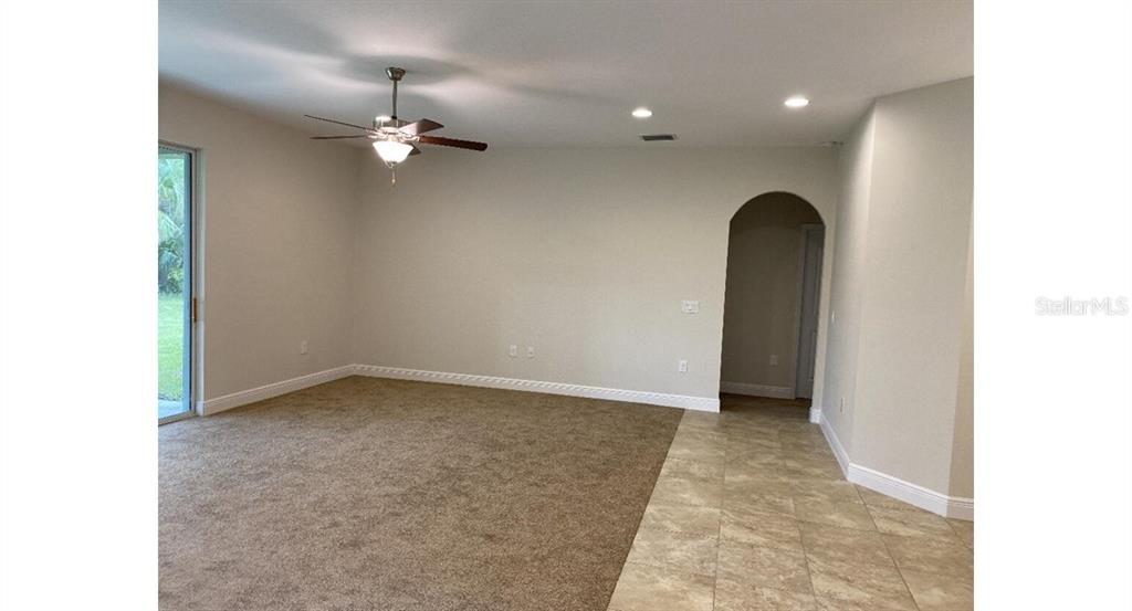 A living room features beige carpet, a ceiling fan, and an arched entryway to another room — 5519 BAKER ROAD, NORTH PORT, FL