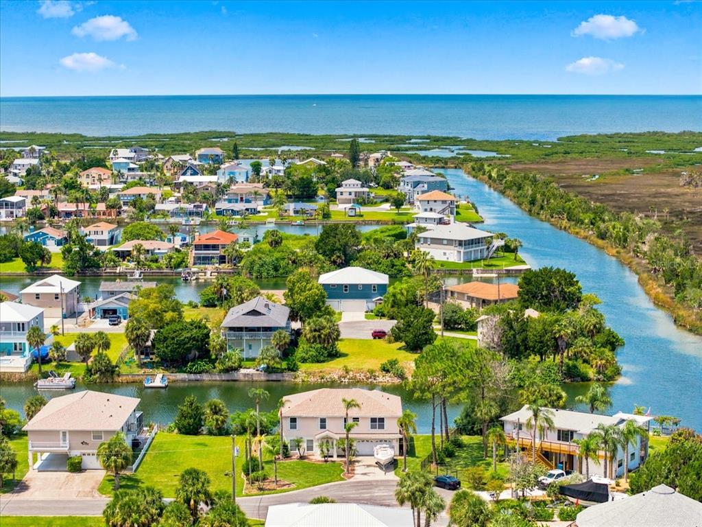An aerial view shows waterfront houses with docks along a canal near a coastal marsh — 3417 FERNLEAF DRIVE, HERNANDO BEACH, FL
