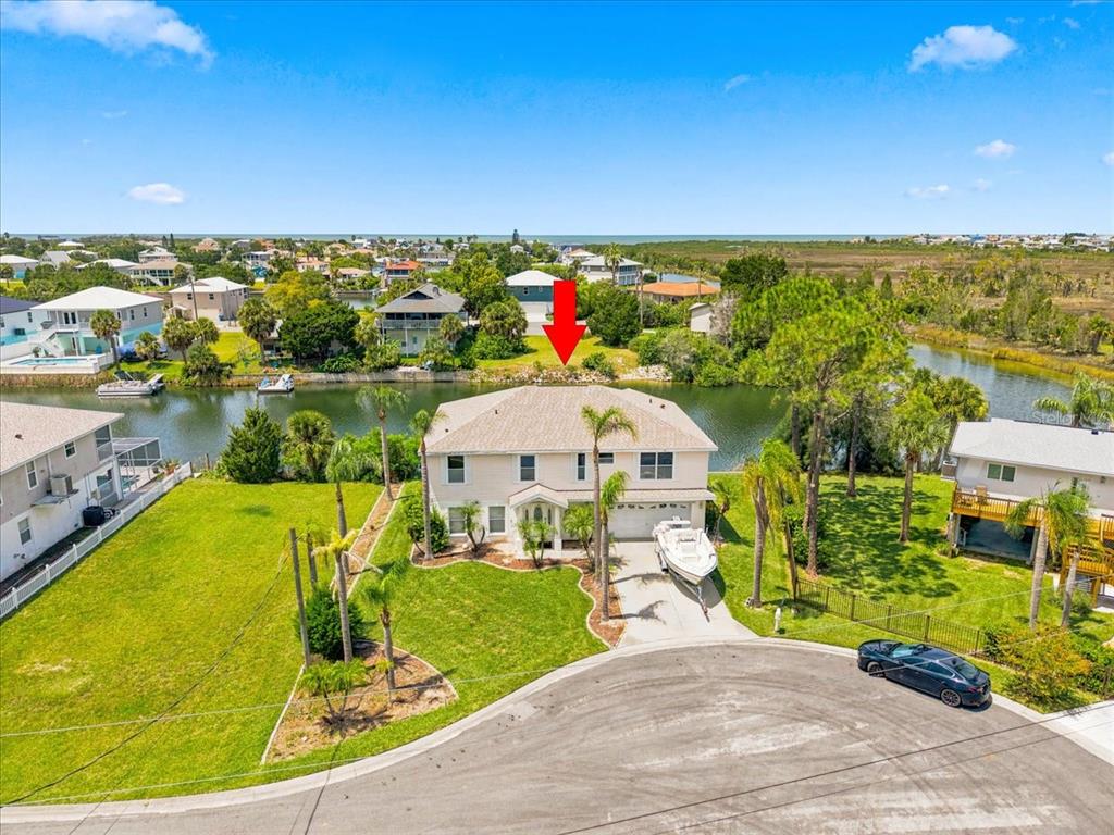 An aerial view shows a two-story house with a boat in the driveway by a canal — 3417 FERNLEAF DRIVE, HERNANDO BEACH, FL