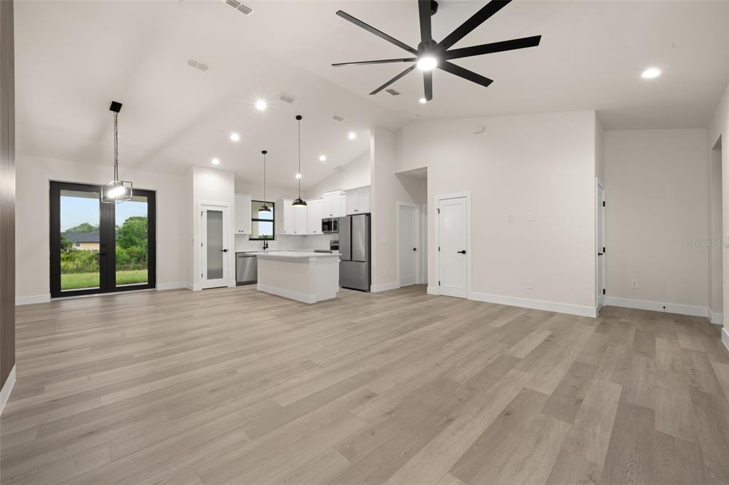 A bright, open-concept kitchen and living area features light wood flooring and vaulted ceilings — 5846 SAN JUAN DRIVE, SEBRING, FL
