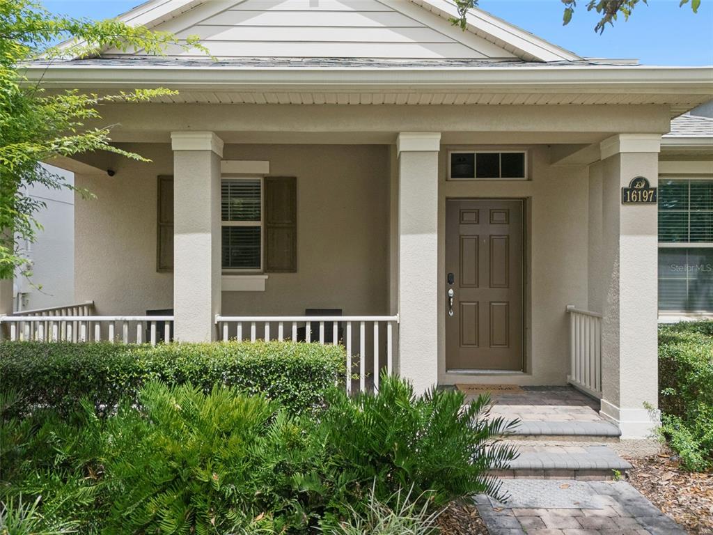 A tan house exterior features a covered front porch with white railings and a brown door — 16197 WIND VIEW LANE, WINTER GARDEN, FL