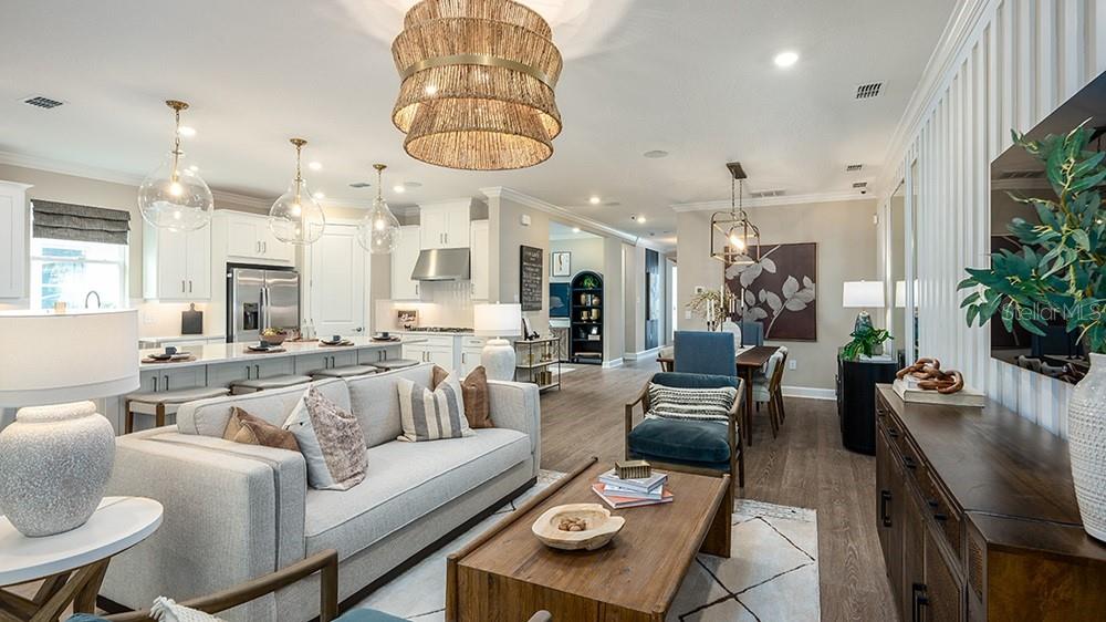 A modern kitchen features white cabinetry, a large center island with seating, and pendant lighting — 1003 TASSLEFLOWER TRAIL, ST CLOUD, FL