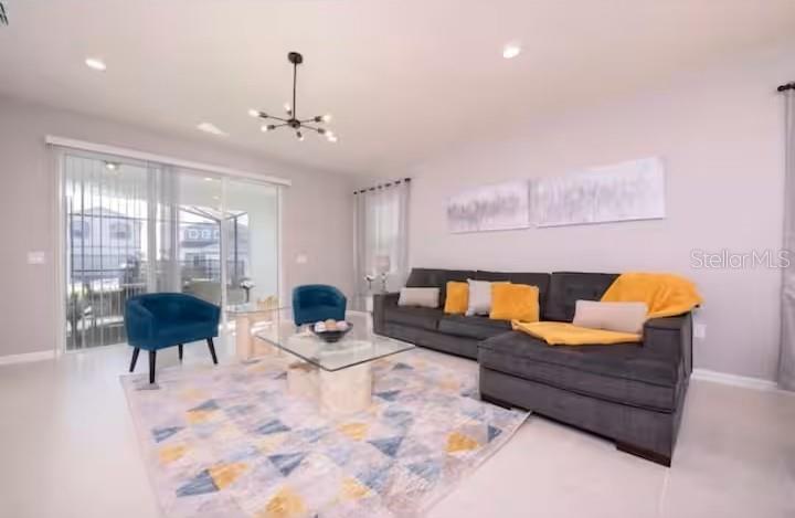 A living room features a gray sectional sofa, blue armchairs, and a glass coffee table — 1837 SUMMER DRIVE, DAVENPORT, FL