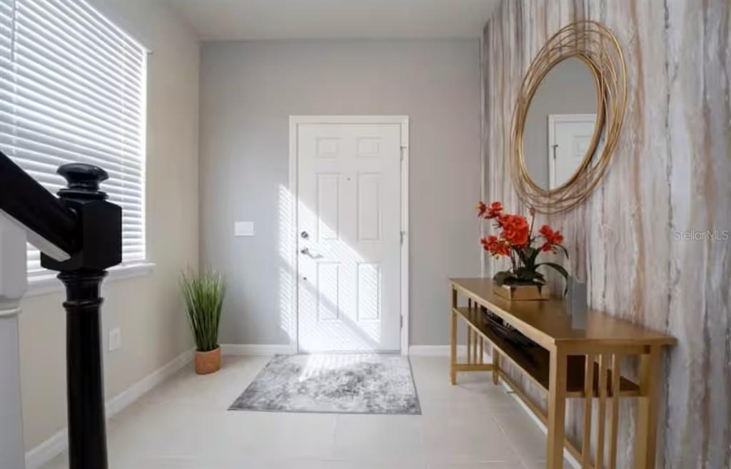 An entryway features a white front door, a gold console table, and a round mirror — 1837 SUMMER DRIVE, DAVENPORT, FL