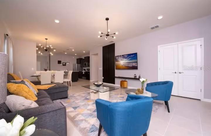 A living room features a grey sectional, two blue armchairs, and a wall-mounted television — 1837 SUMMER DRIVE, DAVENPORT, FL