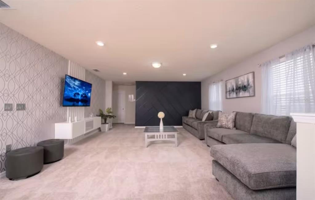 A living room features a gray sectional sofa, a wall-mounted television, and a dark accent wall — 1837 SUMMER DRIVE, DAVENPORT, FL