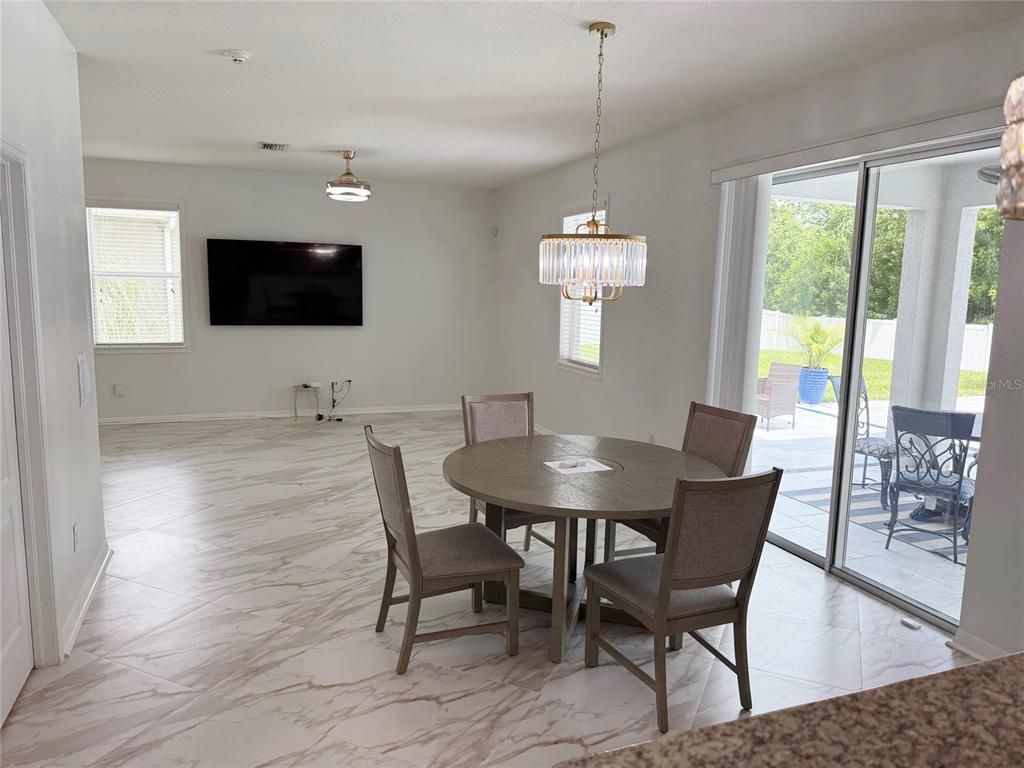 A kitchen features dark wood cabinets, granite countertops, stainless steel appliances, and white tile flooring — 12236 FAIRLAWN DRIVE, RIVERVIEW, FL