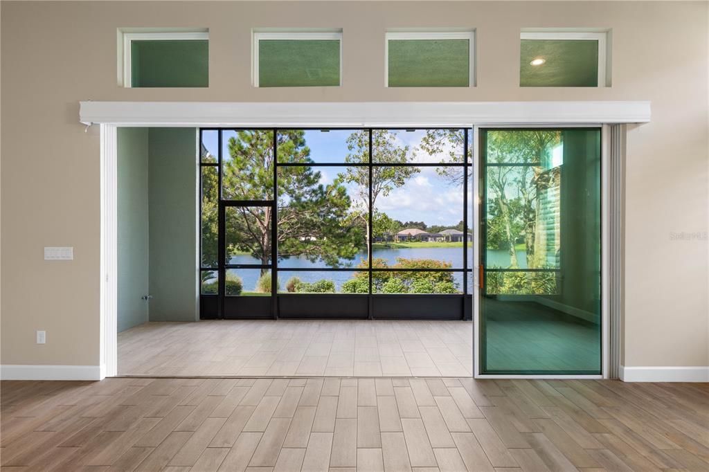 A sunroom with tile flooring features large sliding glass doors opening to a lake view — 661 MAHOGANY RUN, PALM COAST, FL