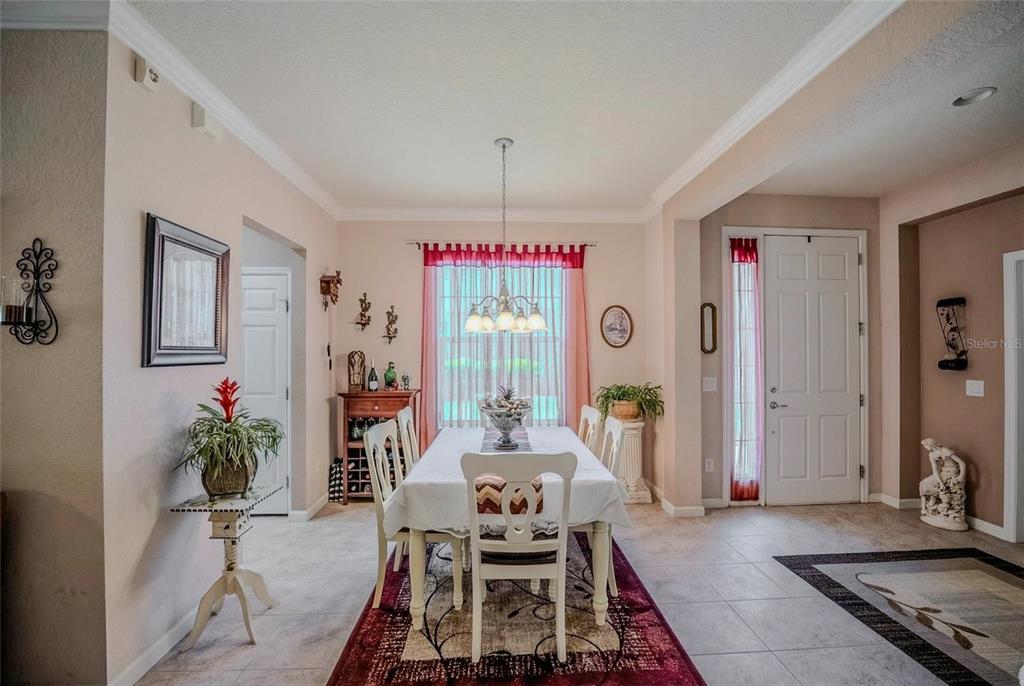 A dining room features a white table with chairs, a chandelier, and tile flooring — 9077 SW 70TH LOOP, OCALA, FL