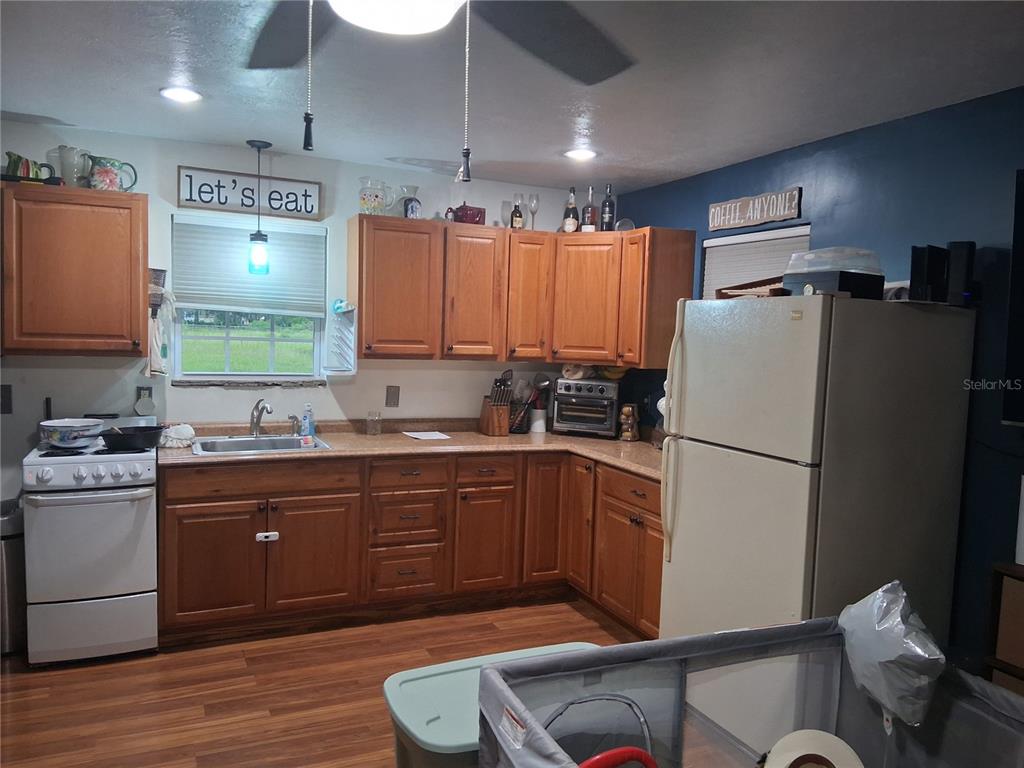 A kitchen features wood cabinets, laminate countertops, a white stove, and a white refrigerator — 10200 CR 749, WEBSTER, FL